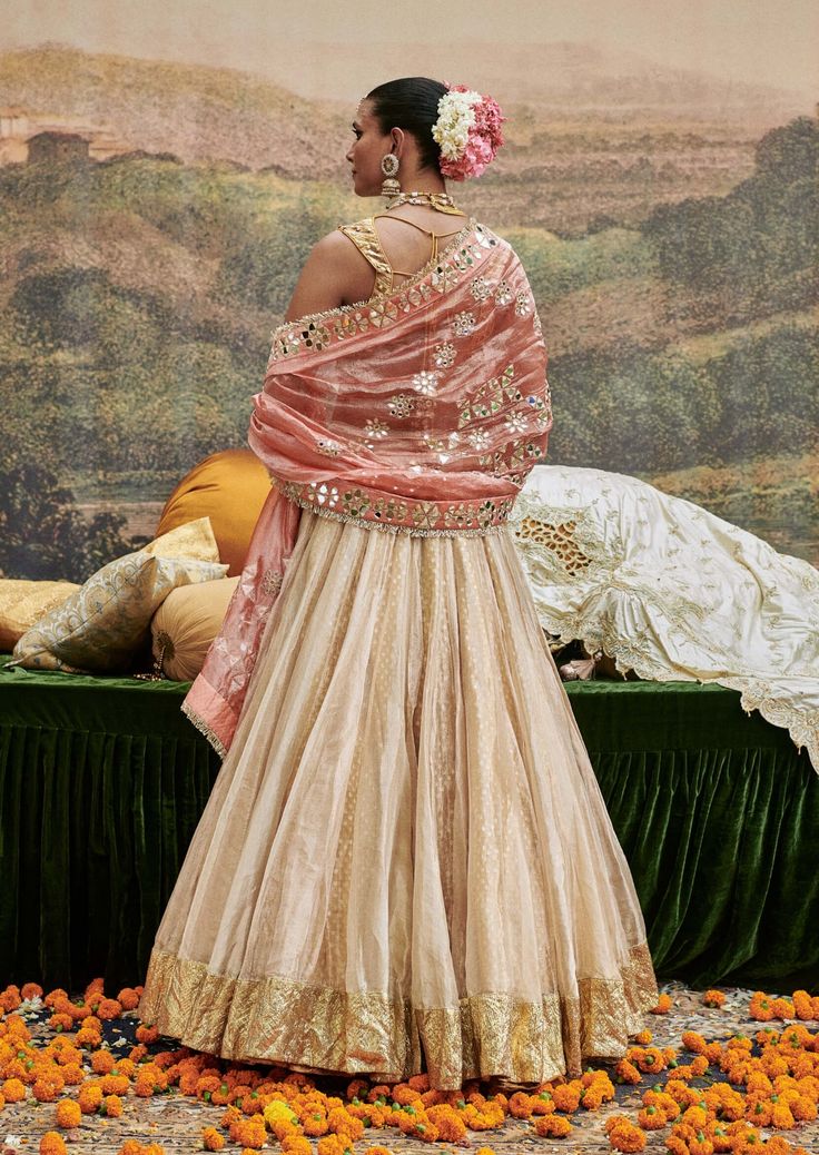 A charming creation, this tissue lehenga features delicate lampi work that adds a touch of elegance. Paired with a stunning mirror work blouse, the ensemble is beautifully completed with a mirror tissue dupatta, creating a cohesive and radiant look. Perfect for festive occasions, this outfit effortlessly combines traditional artistry with contemporary style. Tissue Lehenga, Ivory Lehenga, Tissue Dupatta, Mirror Work Blouse, Beach Wedding Guests, Jacket Cape, Ritu Kumar, Indian Ethnic Wear, Mirror Work