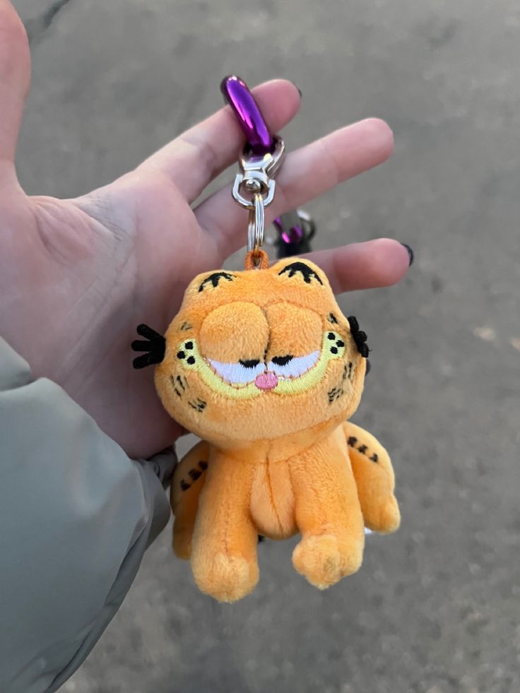 a hand holding a keychain with a small stuffed animal on it's side