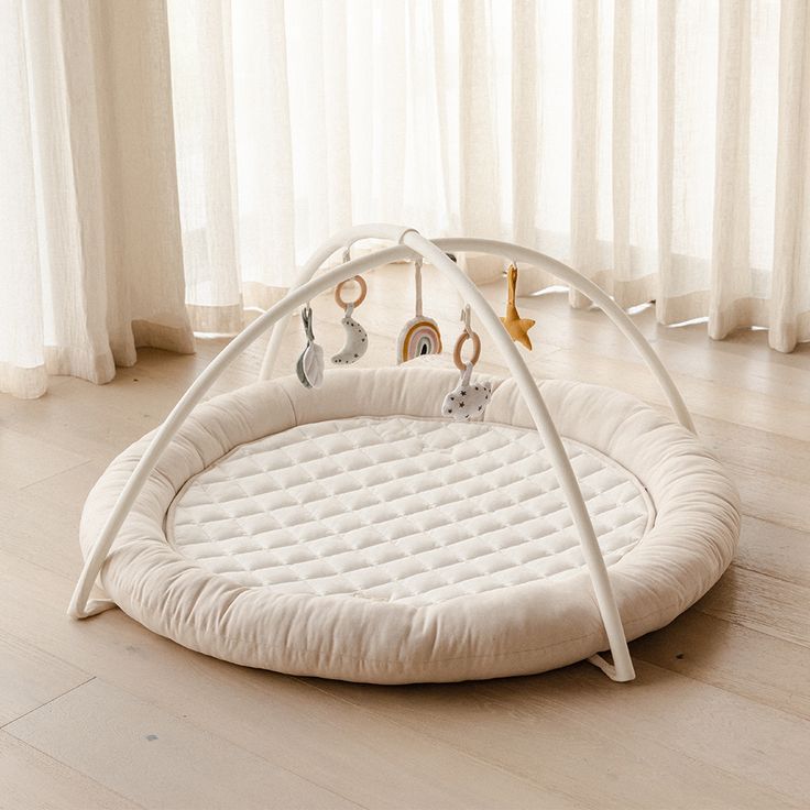 a baby's playpen in the middle of a wooden floor with curtains behind it