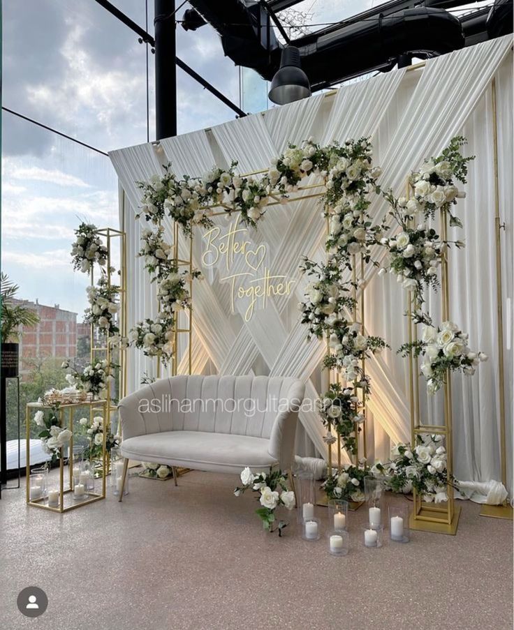 an outdoor ceremony setup with white flowers and greenery on the wall, along with candles