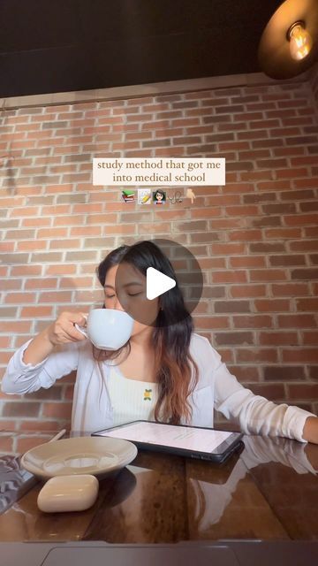 a woman sitting at a table drinking from a cup