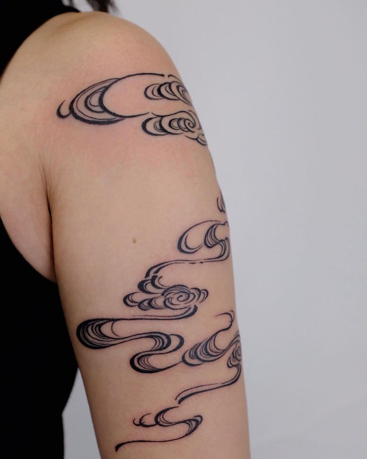 a woman with a tattoo on her arm that has waves coming out of the water