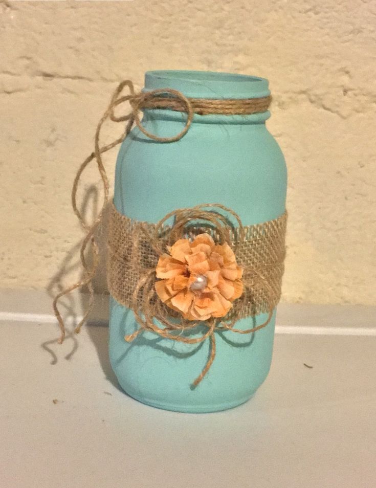 a blue mason jar with burlock and flower on the lid sitting on a table