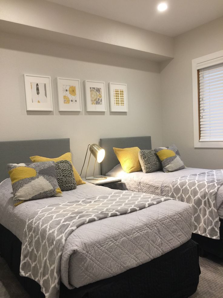 two beds in a bedroom with yellow and gray pillows