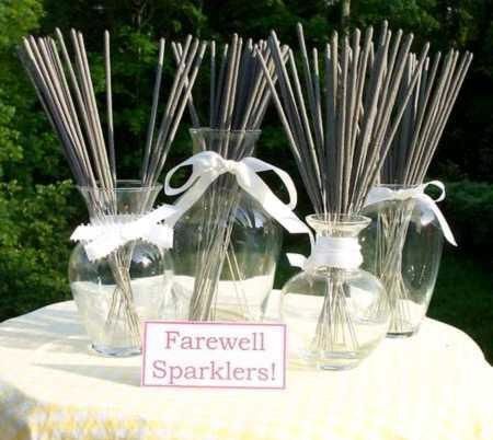 several clear vases with sticks in them are on a table near a sign that says farewell sparklers