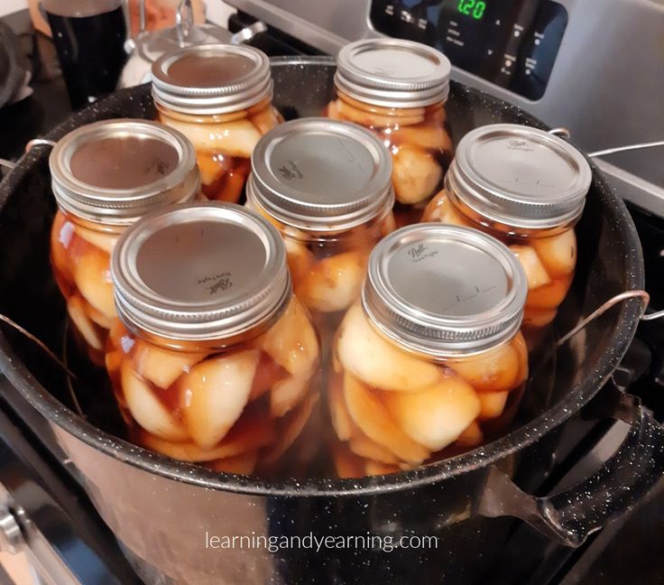 jars filled with pickled apples sitting on top of a stove