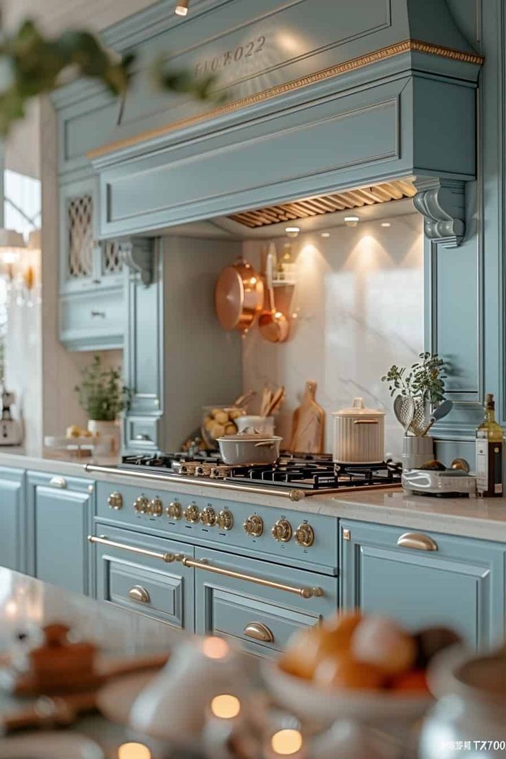 a kitchen with blue cabinets and white counter tops, gold trimmings on the hood