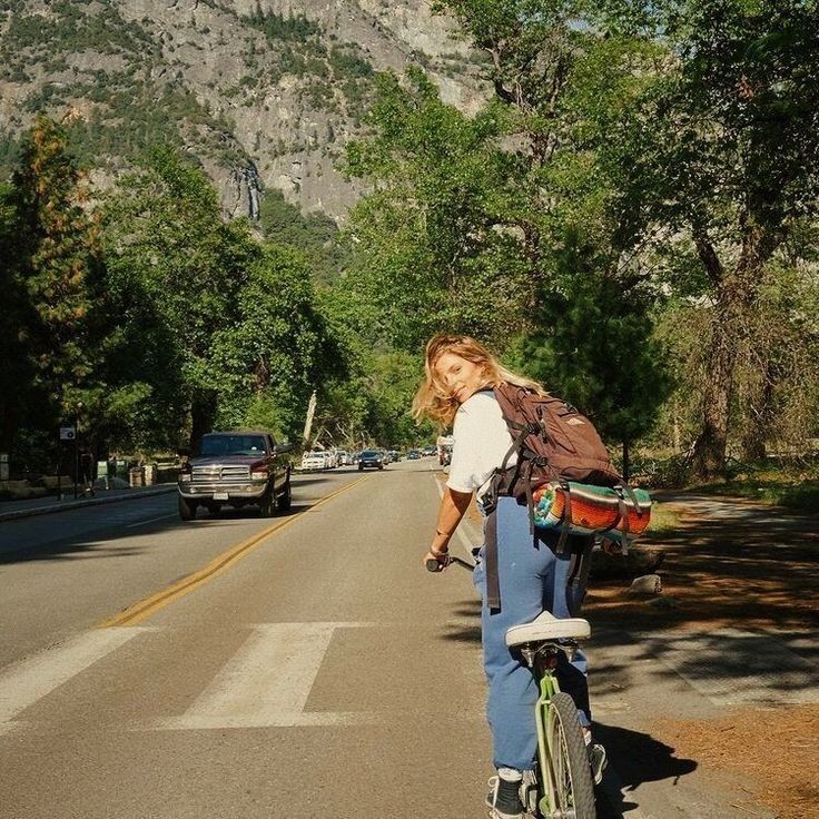 a woman is riding her bike down the street with a backpack on it's back