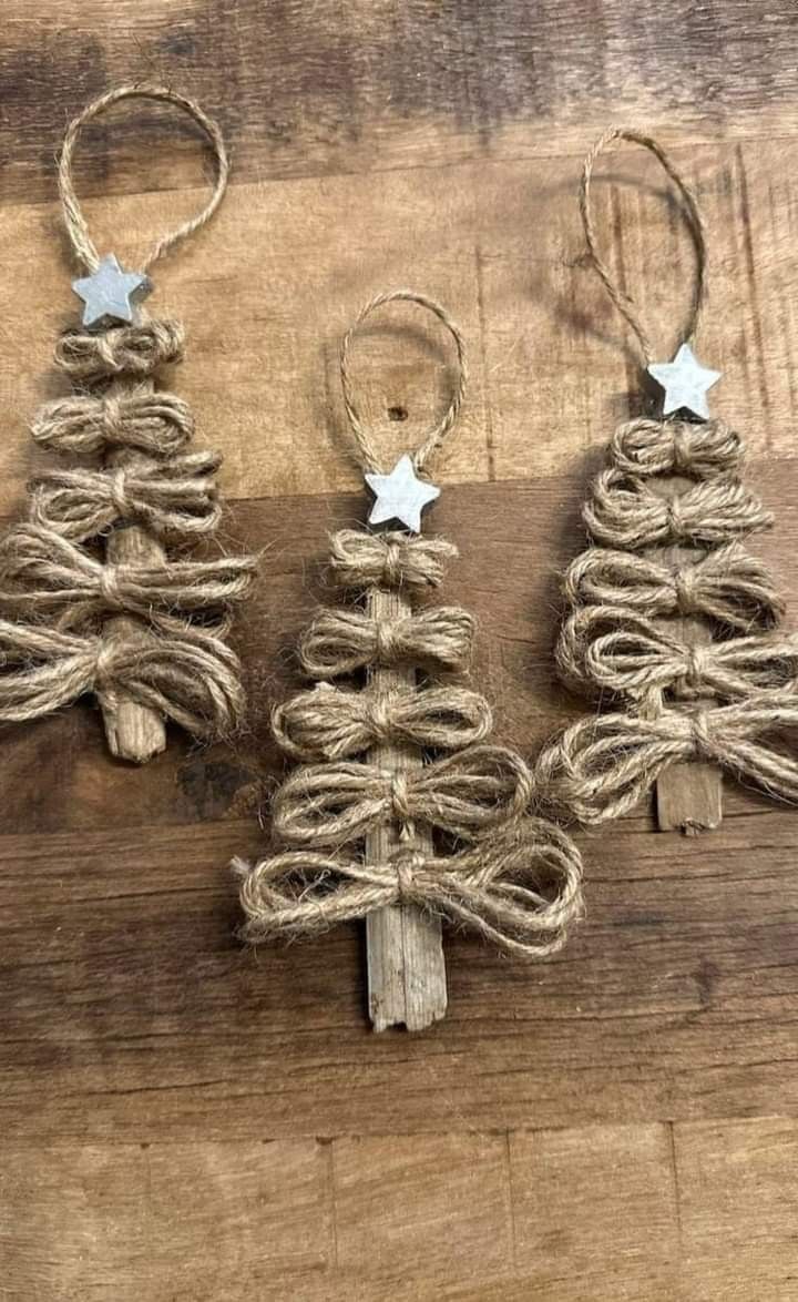 three small christmas trees made out of twine on a wooden board with stars hanging from them