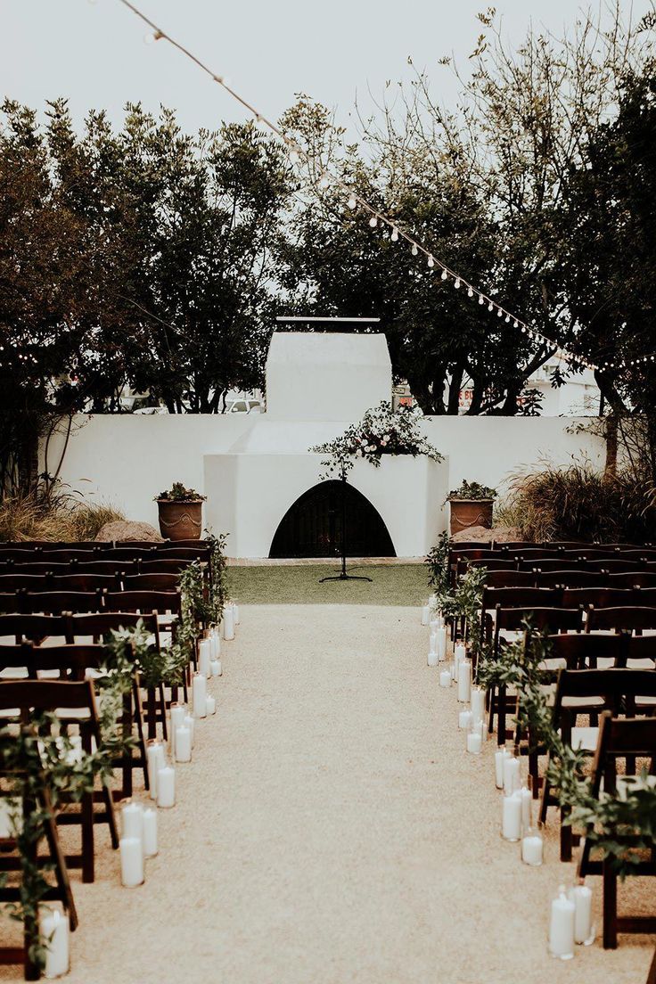 an outdoor ceremony setup with candles and greenery