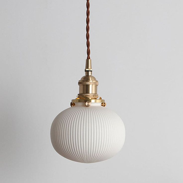 The Alice Rustic Ribbed Capsule Pendant Light in White and Brass seamlessly combines vintage charm with contemporary design. Crafted from high-quality materials, this pendant light features a ribbed glass shade that exudes a warm, inviting glow. The rustic brass accents add a touch of elegance and sophistication to any space. Its versatile white color complements a range of interior styles, making it a perfect addition to your living room, bedroom, or dining area. The adjustable cord allows for easy installation and customization to suit your desired height. Illuminate your home with the classic beauty of the Alice Rustic Ribbed Capsule Pendant Light and create a cozy atmosphere that will impress your guests.Size: 5 to 9 Inch Fixture Width: 3" 5" 5.5" Fixture Height: 8.5" 6" 5" Bulb Includ Clear Glass Pendant Light, Brass Wall Hanging, Ceramic Pendant Light, Ceramic Wall Lights, Rustic Light Fixtures, Bedside Wall Lights, Industrial Ceiling, Farmhouse Pendant Lighting, Wall Mounted Lamps