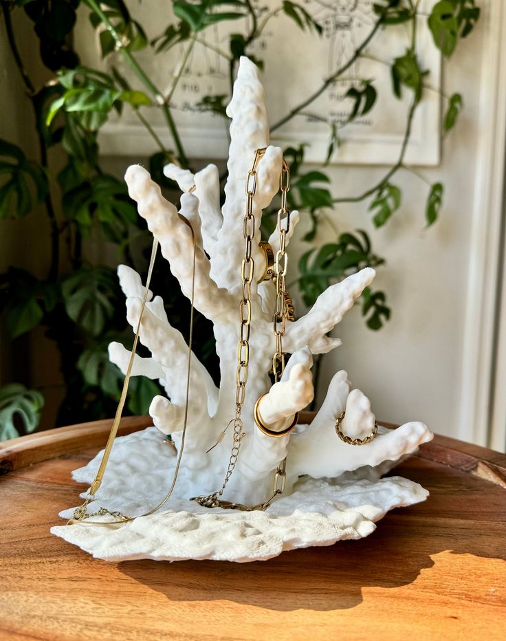 a close up of a small statue on a table with a plant in the background