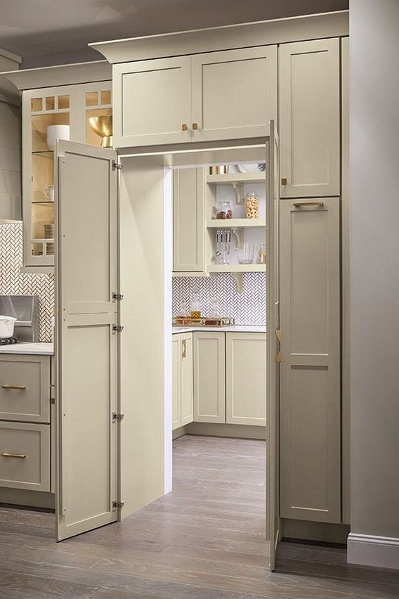 an open door leading to a kitchen with beige cabinets and white counter tops, along with wooden flooring