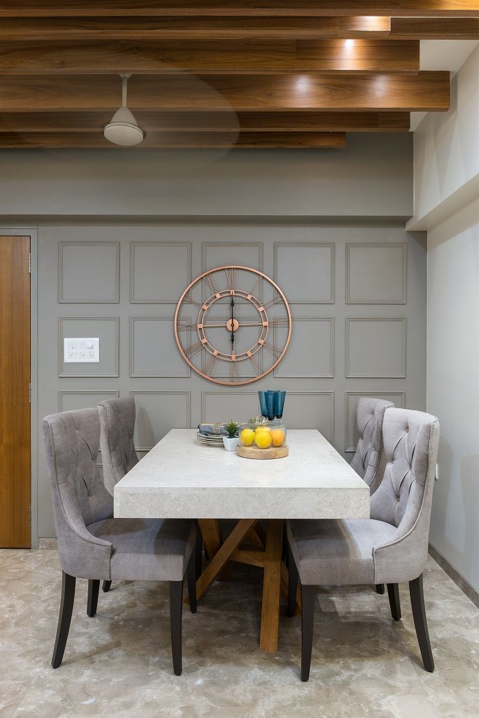 a dining room table with chairs around it and a clock on the wall behind it