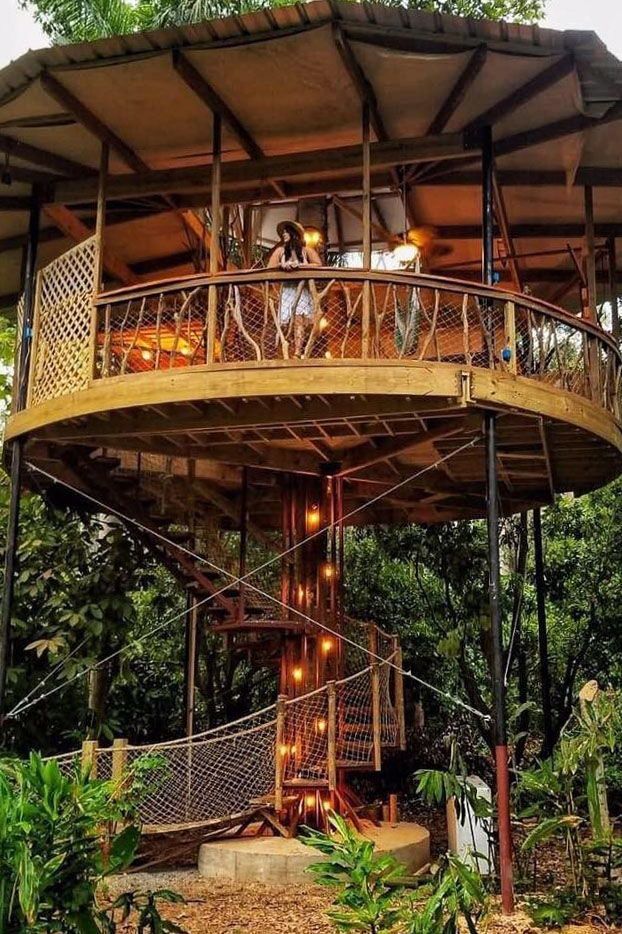 a tree house in the middle of trees with people on top and stairs leading up to it