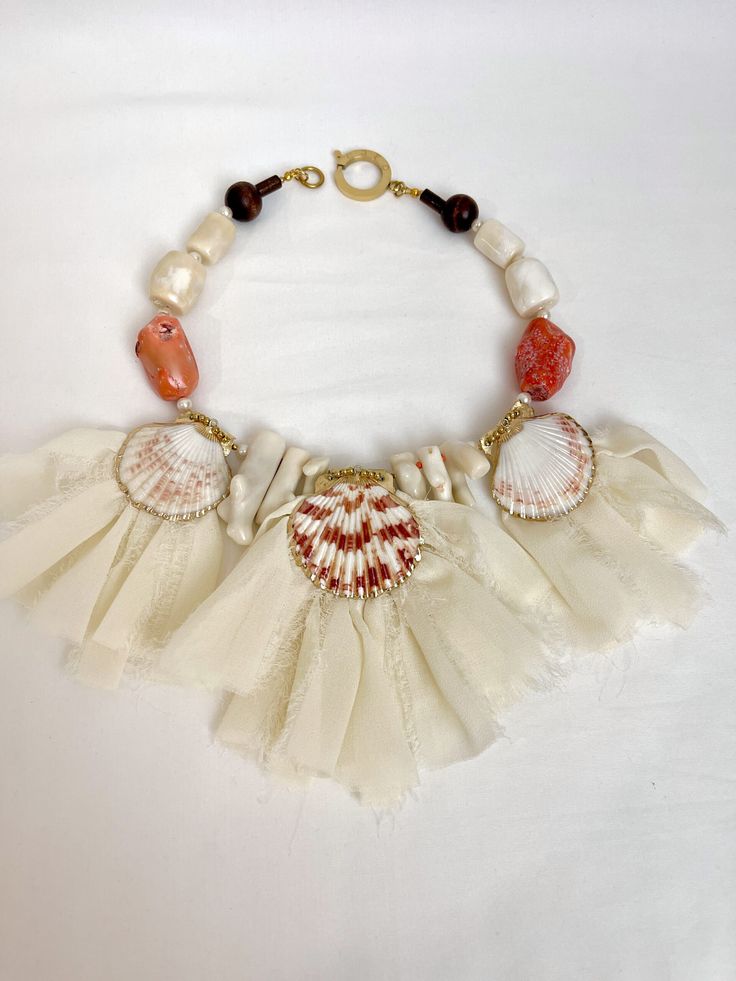 Soft peach colors of natural sea shells, soft orange Coral, natural white Coral, and ivory ribbon.  The necklace measures 18 INC/46 CM long. White Shell Wedding Necklace, Elegant Shell Necklace For Summer, White Ocean-inspired Necklace In Mother Of Pearl, White Mother Of Pearl Ocean-inspired Necklace, Unique Orange Beach Necklaces, Unique Orange Necklace For Beach, Unique Orange Necklaces For The Beach, Unique White Shell For Vacation, Unique White Shell-shaped Necklace