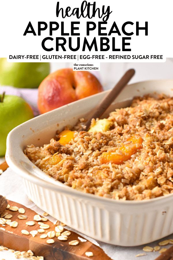 healthy apple peach crumble recipe in a white baking dish with oats and apples on the side