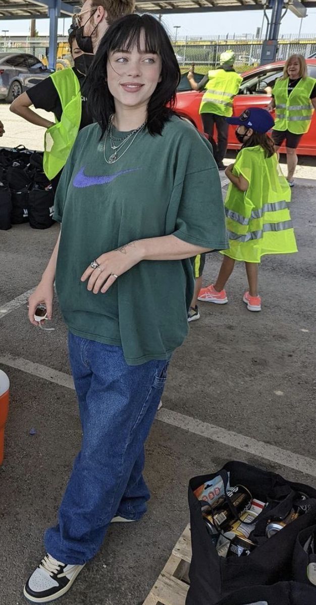 a woman is standing in the middle of a parking lot with her arms up and smiling