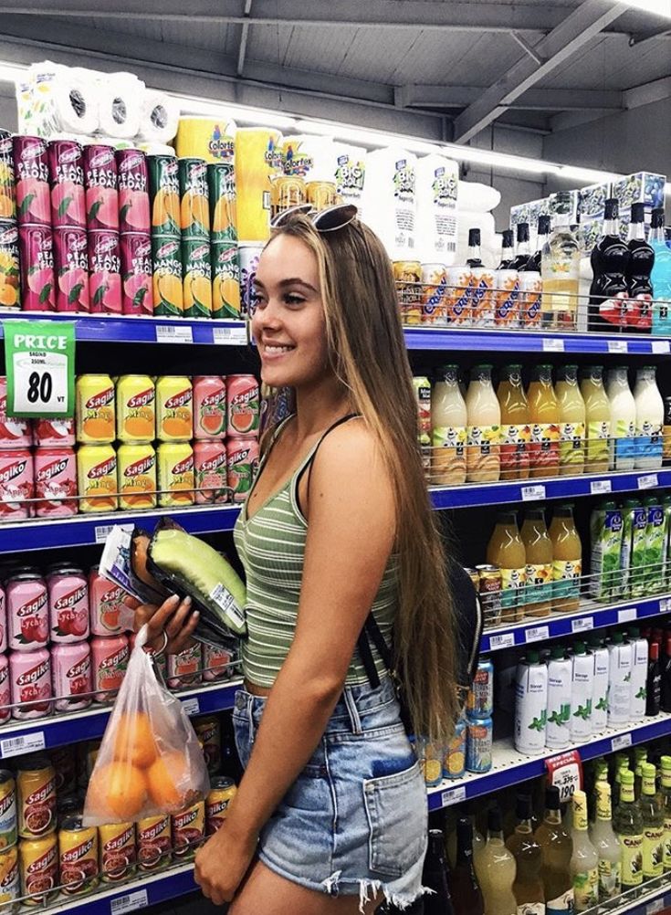 a woman standing in front of a display of drinks and juices at a grocery store