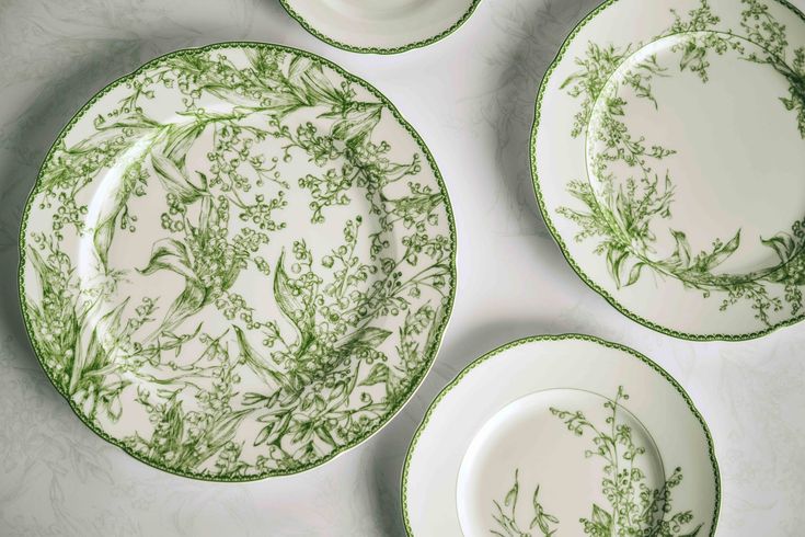 four plates with green floral designs on them