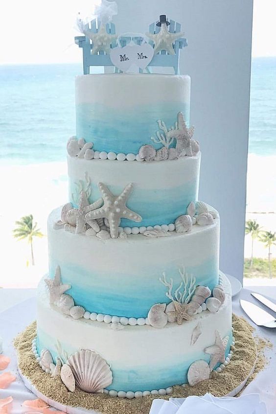 a blue and white wedding cake with seashells on it