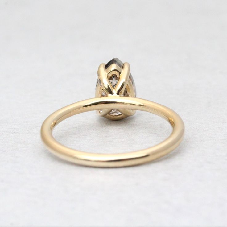 a yellow gold ring with a diamond on the top and bottom, sitting on a white surface