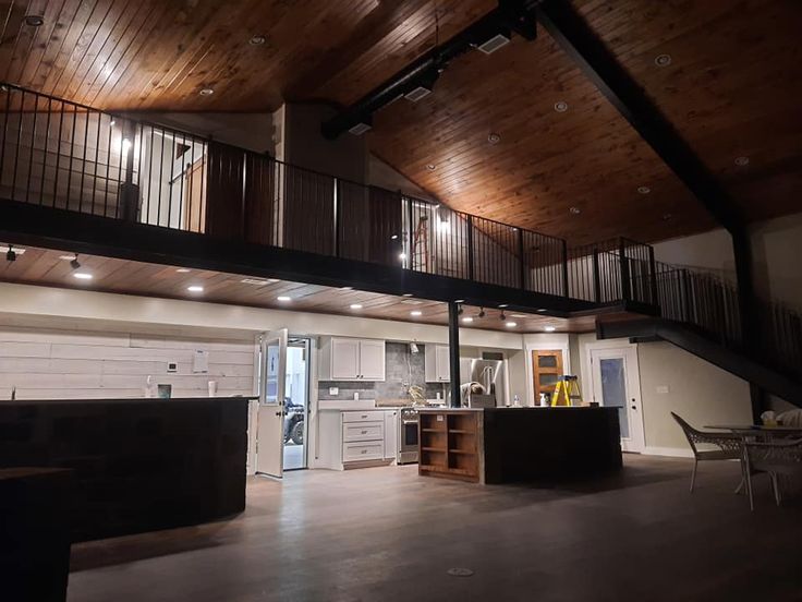 an open living room and kitchen area in a house with wooden ceilings, exposed beams, and wood flooring