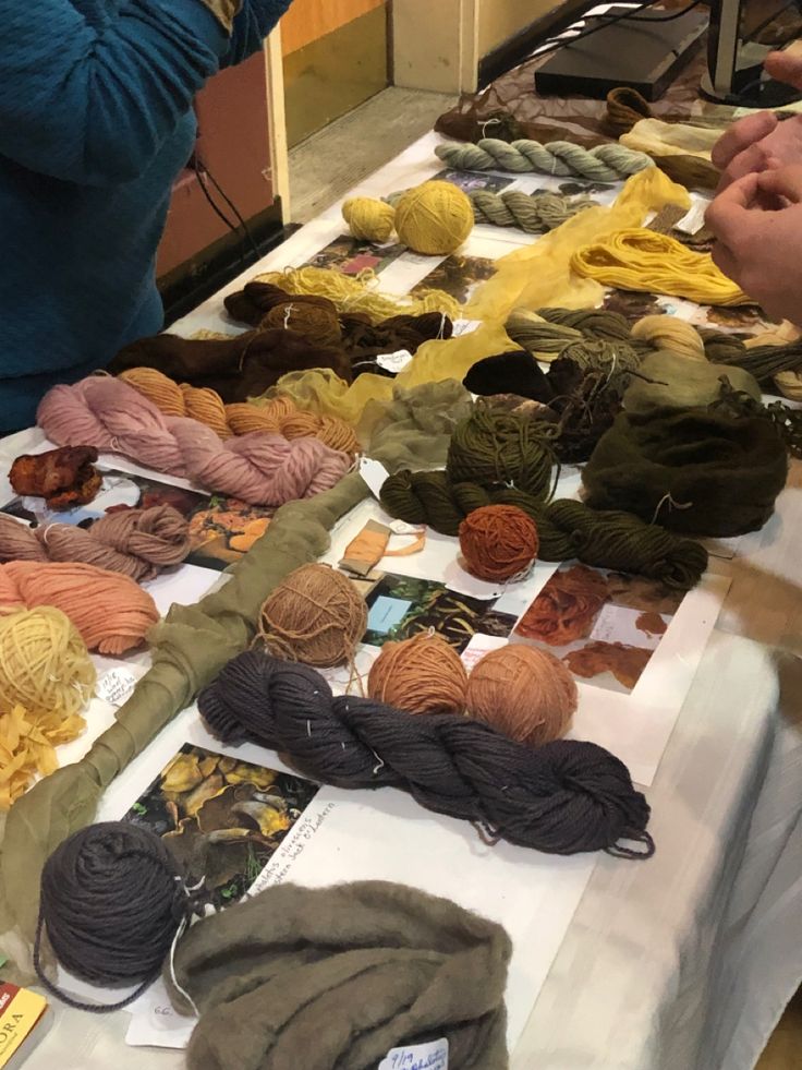 several skeins of yarn are laid out on a table with people looking at them