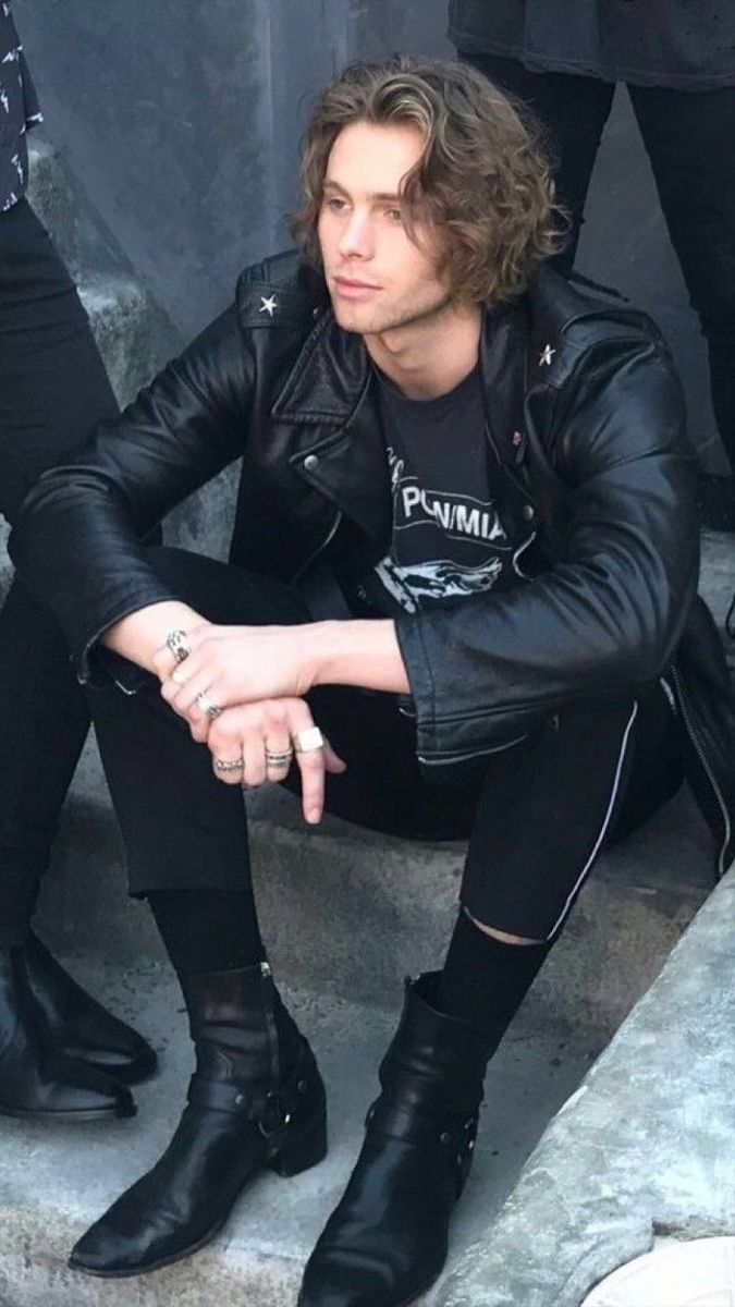 a man sitting on the ground wearing black boots