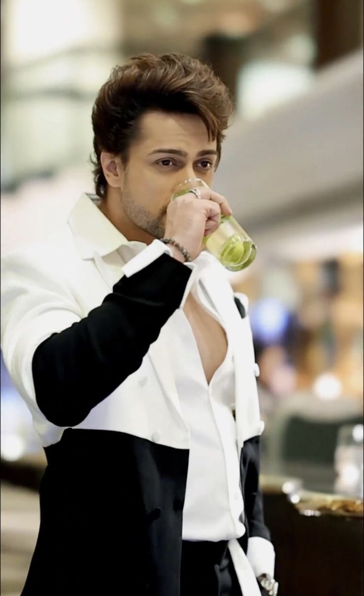 a man drinking from a bottle while wearing a suit