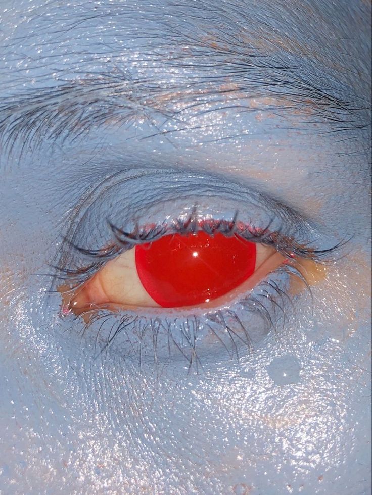 a close up of an eye with blue and red paint on it's iris