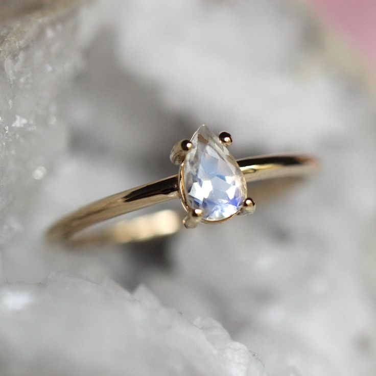 Moonstone is known as a stone of protection and is associated with the crown and third eye chakras.  Bring the moonstone's protective energy into your life with our 14K "Chakra" ring!  Handcrafted from 14K gold and featuring a pear-shaped rainbow blue moonstone in a bezel setting.  - Rainbow blue moonstone measures 6mm by 4mm, very high VS quality, picks up colors of pink, yellow, blue, and purple   - Choose between soldi 10K or 14K gold - Round band measures 1.3mm in width Processing Times -  C White Moonstone Celestial Ring In 14k Gold, White Celestial Moonstone Ring In 14k Gold, 14k Gold Spiritual Moonstone Ring, 14k Gold Moonstone Ring For Anniversary, Spiritual 14k Gold Moonstone Ring For Anniversary, Celestial White Moonstone Ring With Halo, Celestial Style White Moonstone Ring With Halo, Spiritual Moonstone Teardrop Ring, Spiritual Teardrop Moonstone Ring