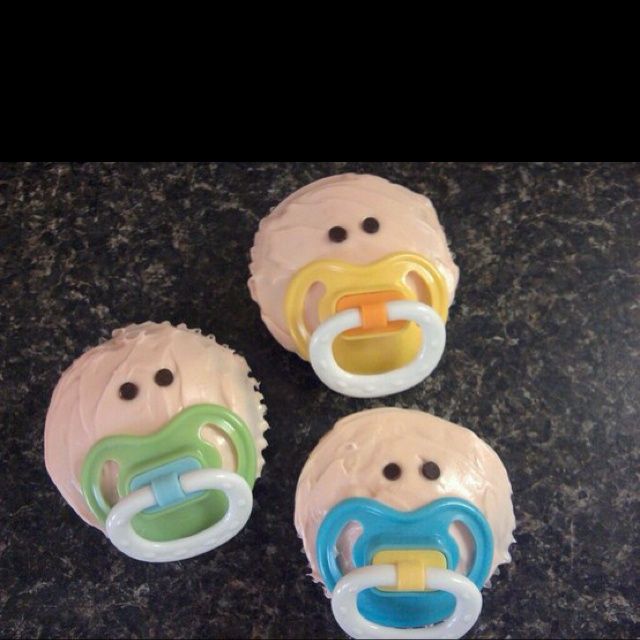 three baby pacifier cupcakes sitting on top of a counter