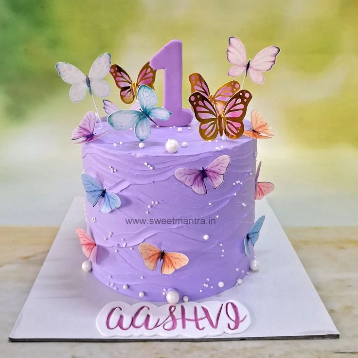 a purple cake decorated with butterflies and the number one