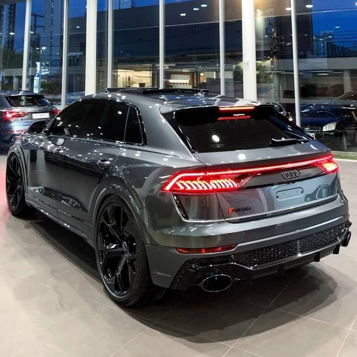 the rear end of a grey car parked in a showroom