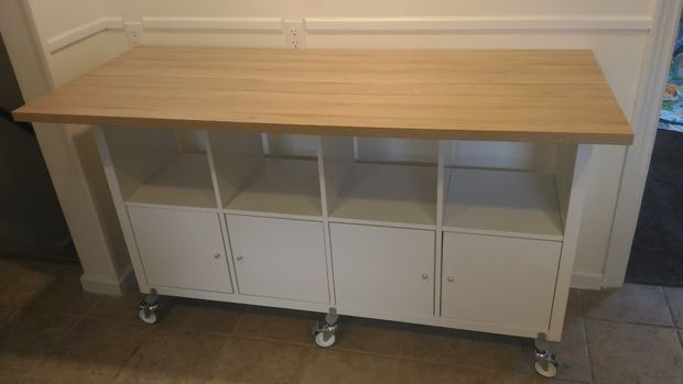 a wooden table sitting on top of a white cabinet next to a wall mounted tv