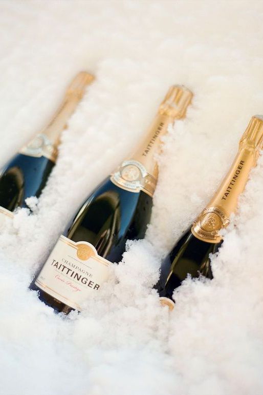 three bottles of champagne sitting on top of snow covered ground next to eachother