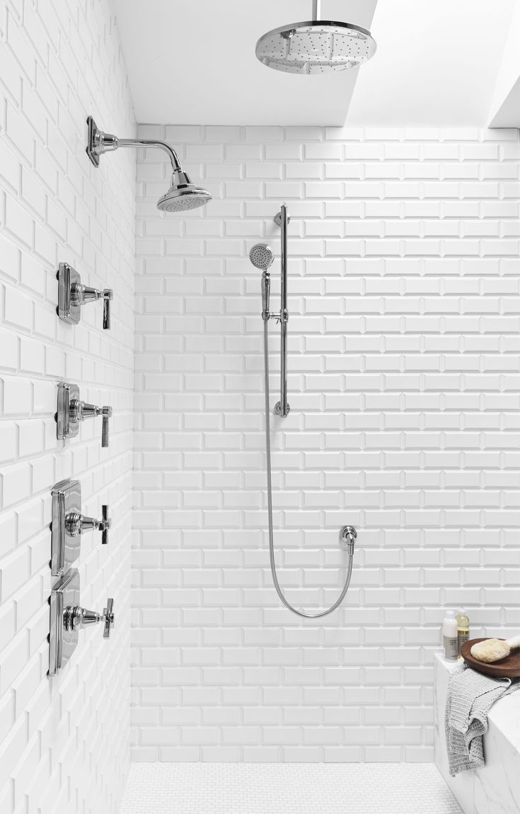 a bathroom with white brick walls and an open shower head in the corner, along with two faucets on either side of the bathtub