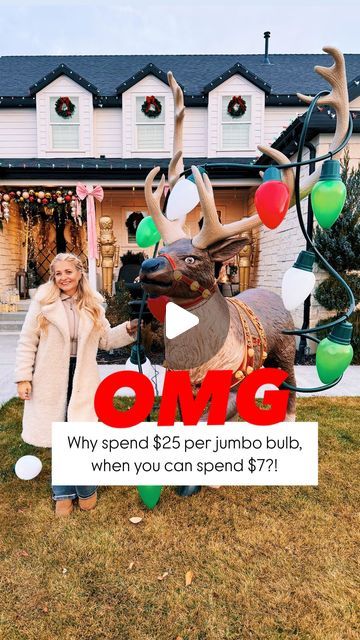 a woman standing in front of a fake reindeer with balloons on it's antlers