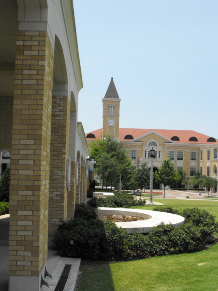 a building with a clock tower in the middle of it's front lawn area