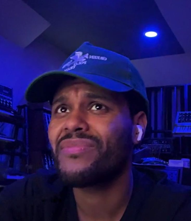 a man wearing a blue hat in front of a recording equipment room with lights on