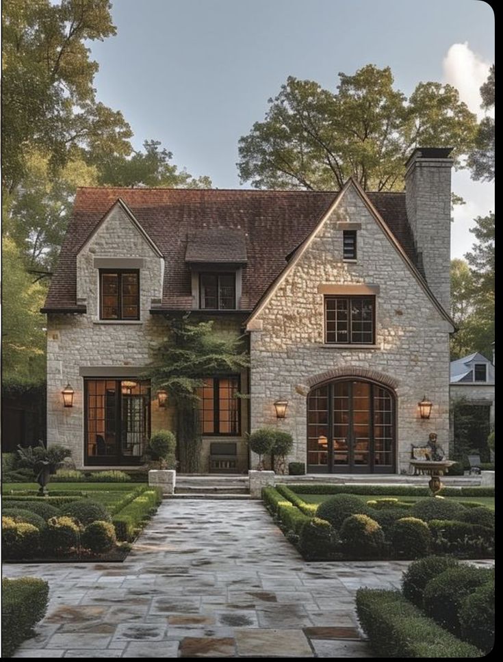 a large brick house with lots of windows and bushes in front of the entrance to it