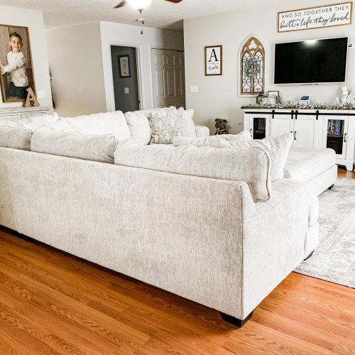 a living room with white furniture and wood floors