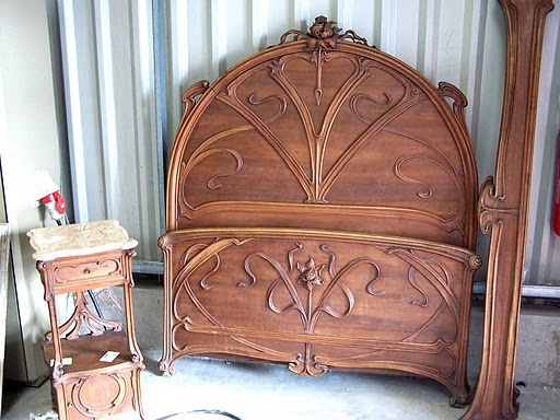 a wooden bed frame sitting next to two nightstands and a mirror on the floor