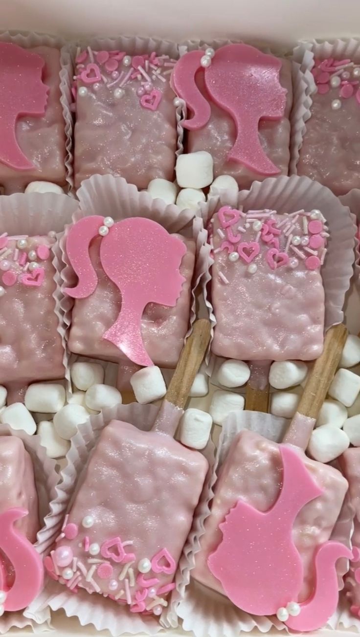 pink and white desserts in a box with wooden utensils on the side