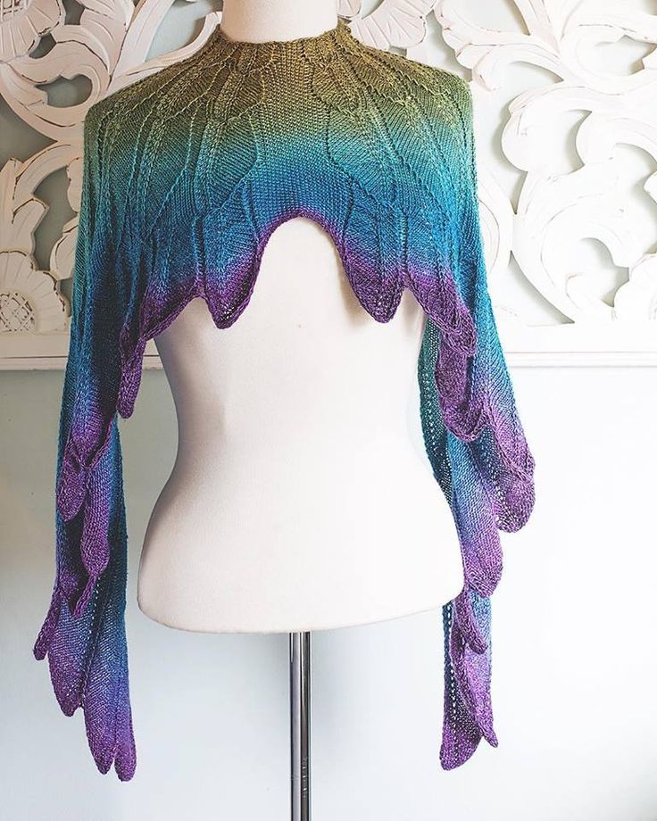 a white mannequin wearing a purple and green knitted shawl over it's shoulder