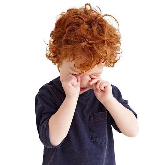 a little boy with red hair is holding his hands to his face