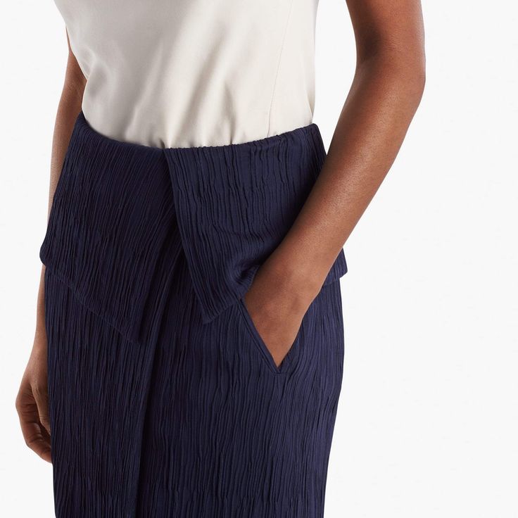 Sizing tip: This skirt runs large. Our stylists recommend ordering one size down. Inspired by classic tuxedo details, this sophisticated skirt features an angular, folded waist detail that creates a peplum-like silhouette. This season, we’ve updated it in a luxurious Italian knit with a pleated texture that allows for shaping and contouring in all the right places. Besom pockets add a little shine, while a secure underlayer keeps you feeling secured and well-covered. Modern Structured Bottoms For Formal Occasions, Modern Structured Formal Bottoms, Elegant Asymmetrical Skirt With Accordion Pleats, Formal Fitted Draped Skirt With Folds, Modern Structured Office Bottoms, Fitted Accordion Pleats Skirt For Workwear, Elegant Asymmetrical Pleated Relaxed Skirt, Formal Asymmetrical Accordion Pleated Skirt, Chic Fitted Draped Skirt With Folds