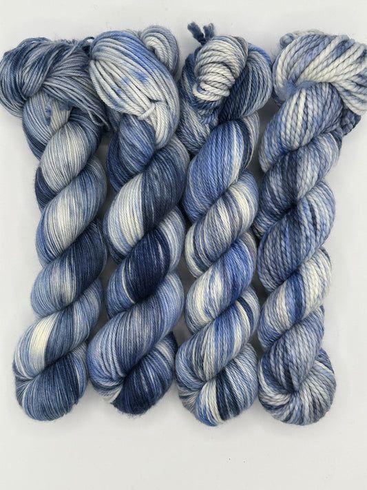 three skeins of blue and white yarn on a white surface with one skein in the middle