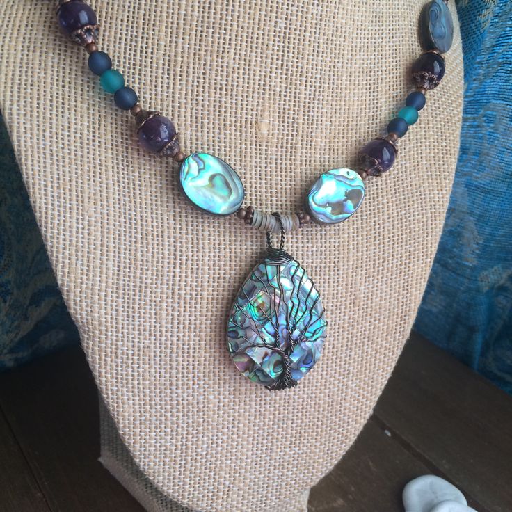 Abalone necklace set shell pendant necklace tree of life boho necklace tribal beach necklace ocean puka surf set unique jewelry for women This beauty has an inlaid puma, abalone and mother of pearl 75mm pendant, with hand wired tree of life, 22mm abalone shell double sided beads, 10mm amethyst gemstone beads, 6mm blue and teal beach glass beads, 5mm rare golden lip oyster puka shell beads, 13 0 seed beads, copper findings and toggle clasp. Length is 22 inches approx. Earrings: 40mm approx with d Bohemian Wire Wrapped Jewelry, Bohemian Wire Wrapped Jewelry For Festival, Hippie Festival Jewelry With Natural Stones, Festival Hand Wrapped Dangle Jewelry, Festival Hand-wrapped Dangle Jewelry, Adjustable Turquoise Nature-inspired Jewelry, Unique Abalone Shell Jewelry For Beach, Unique Wire Wrapped Beach Jewelry, Artisan Wire Wrapped Beach Jewelry